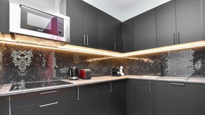 A modern kitchen with dark cabinets, a microwave, a coffee maker, and a toaster. - Authentic Apartment - 2br/6p - Near Opera Garnier (Paris)