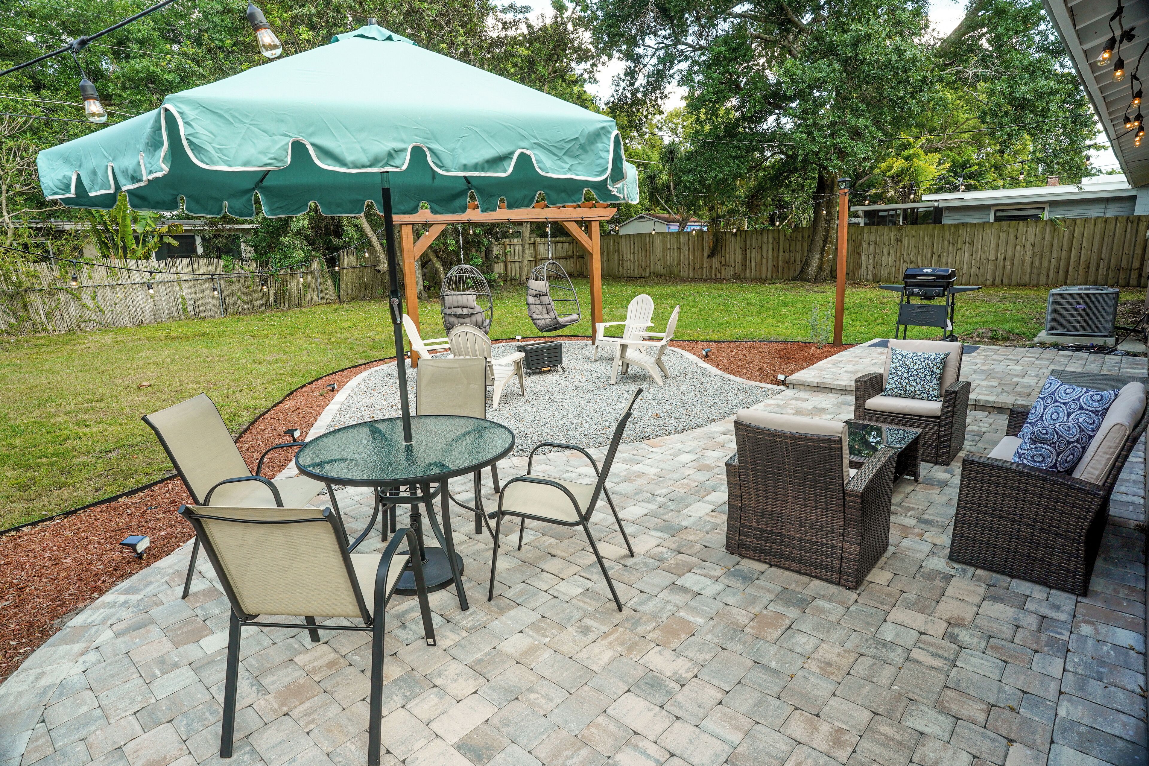 An outdoor patio with a pergola, seating, and a grill area.