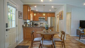 A kitchen with wooden cabinets, a central island, and a dining area with chairs and a table.