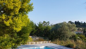 A rectangular swimming pool with a tiled deck, surrounded by greenery and trees. - Lovely apartment with swimming pool and exterior (Gabian)