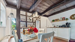 Una cocina con armarios blancos, techo de madera y un comedor con mesa y sillas.