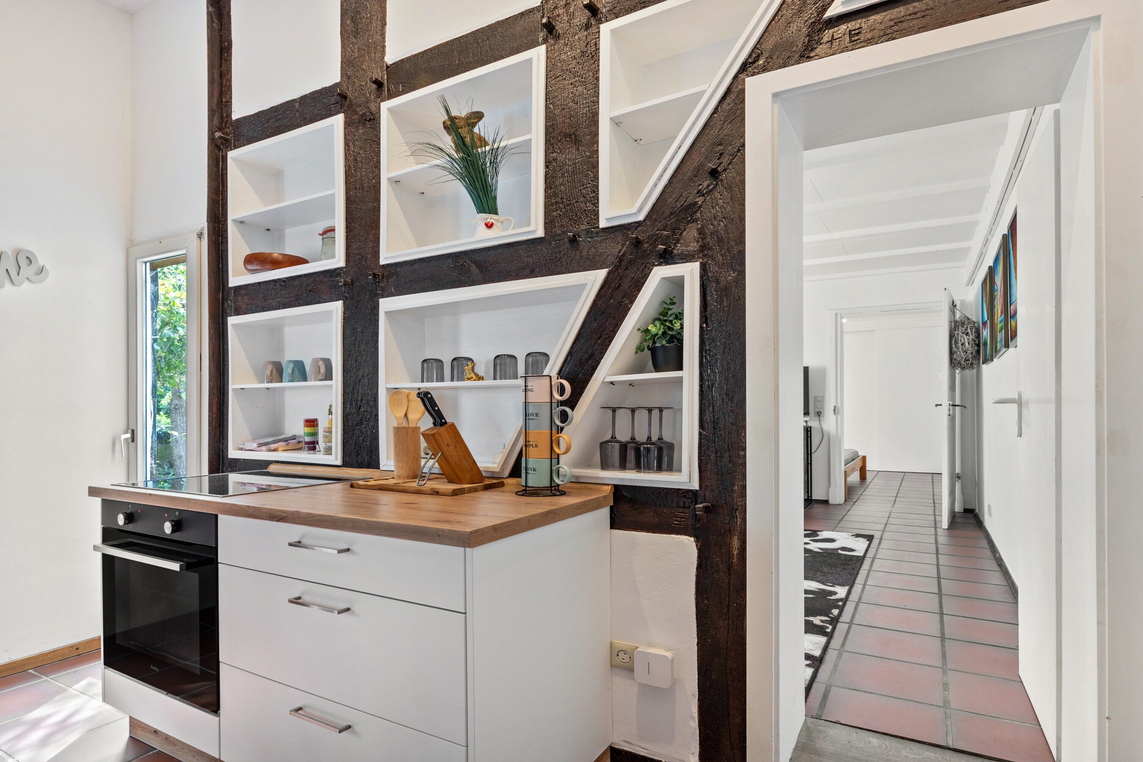 A kitchen with white cabinetry, a wooden countertop, and a built-in shelf unit.