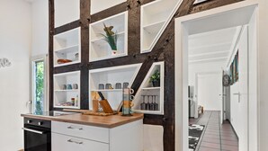 Una cocina con armarios blancos, encimera de madera y una estantería empotrada.