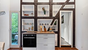 Una cocina con armarios blancos, encimera de madera y estanterías empotradas.
