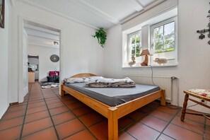 Una camera da letto con un letto di legno, una finestra vista, un termosifone e una pianta.