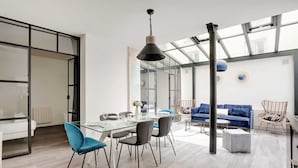 A modern interior with a dining area, a sofa, and a large window. - Elegant Apartment -2br/4p - Sacre-coeur (Paris)