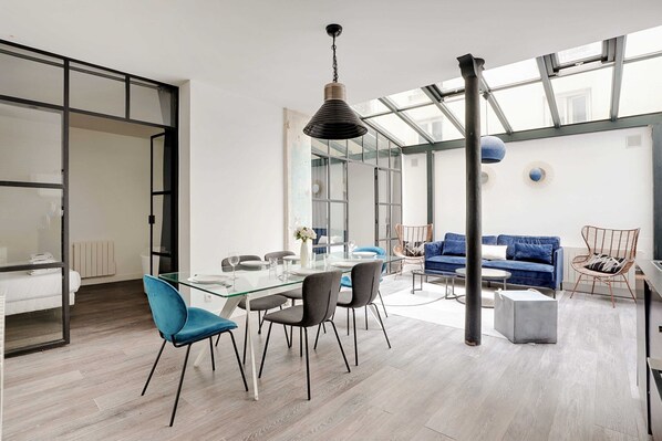 A modern interior with a dining area, a sofa, and a large window.
