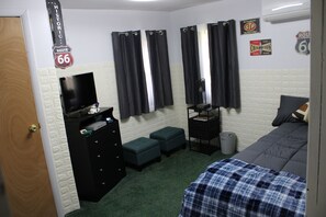 A room with a bed, a dresser, a television, and a sign on the wall. - Cozy Creekside Retreat near Watkins Glen (Beaver Dams)