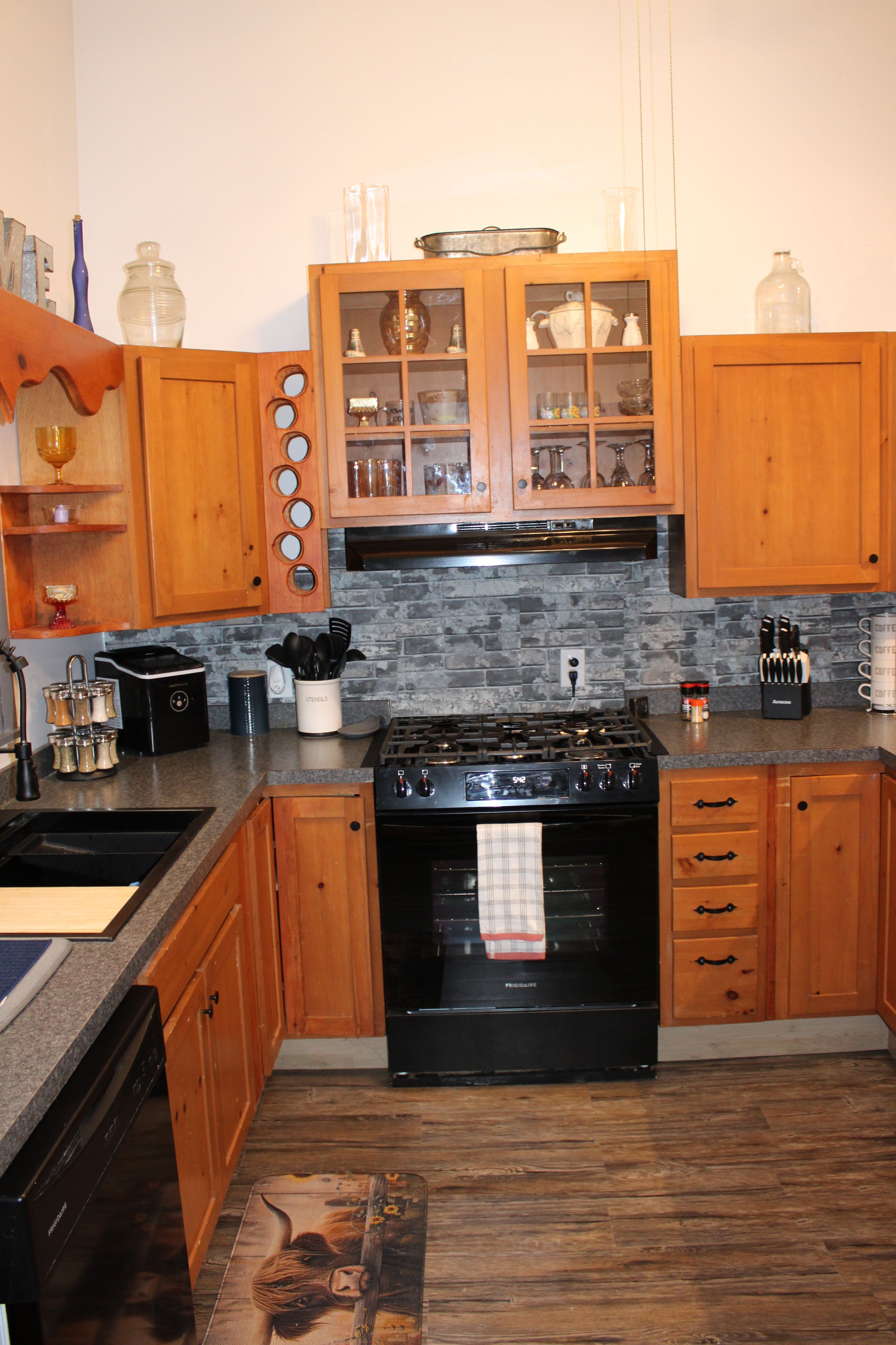 A kitchen with wooden cabinets, a black stove, and a granite countertop.