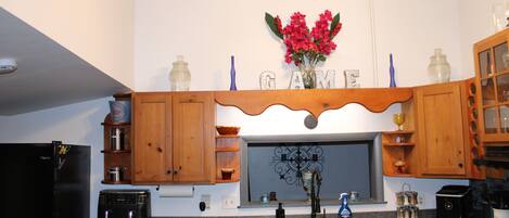 Cocina con armarios de madera, horno empotrado, lavavajillas y ventana con un salpicadero decorativo.