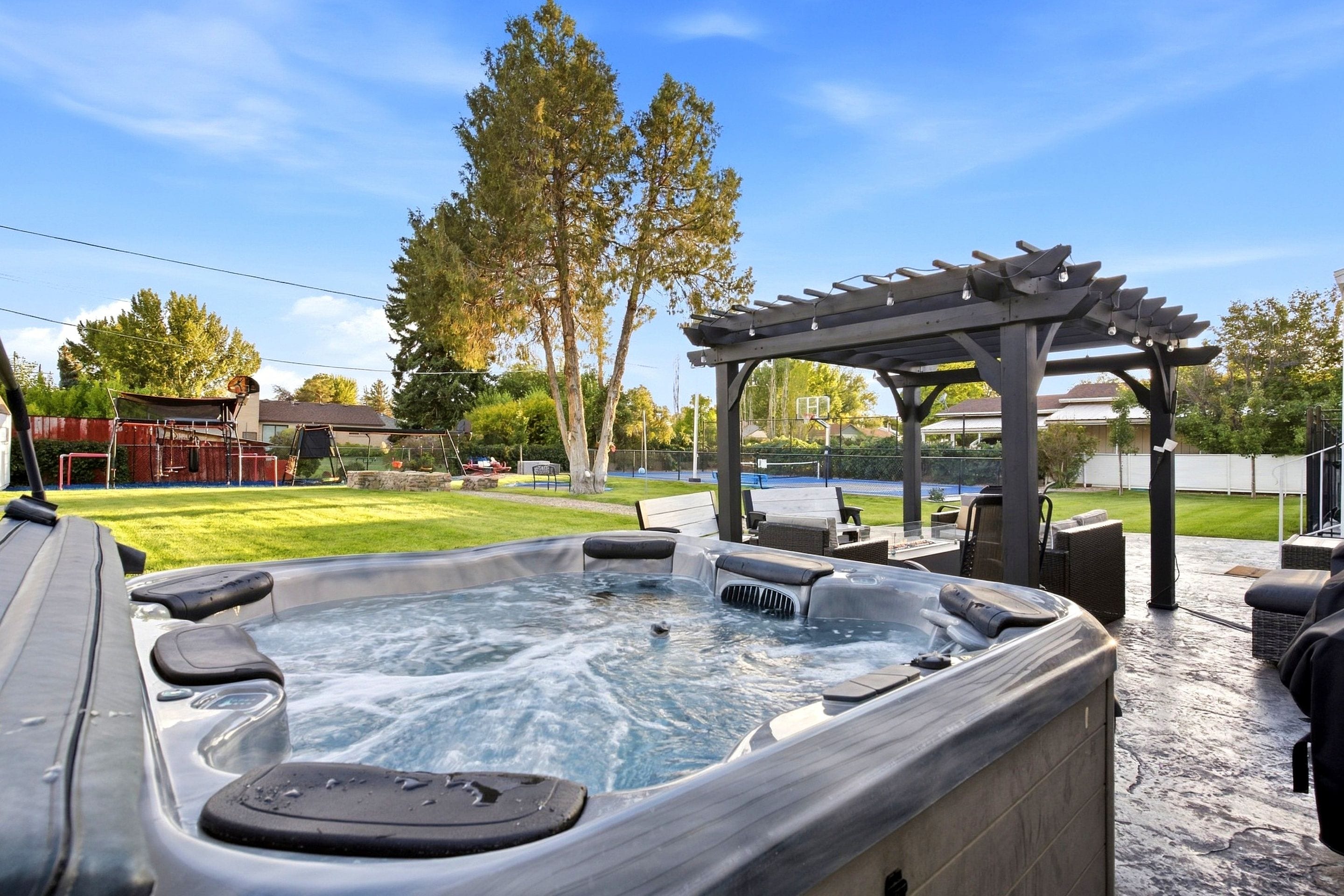 A hot tub with a pergola and outdoor seating area.