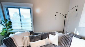A modern living room with a large L-shaped sectional sofa, a small side table, and a floor lamp. - Vernal Sport Court Base Camp (Vernal)
