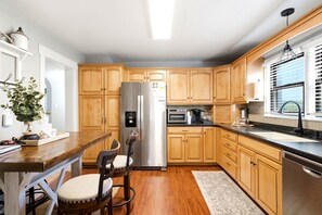 A modern kitchen with wooden cabinets, stainless steel appliances, a built-in oven, and a window with blinds. - Vernal Sport Court Base Camp (Vernal)