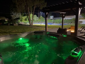 An outdoor hot tub area with green lighting, a basketball hoop, and a fire feature. - Vernal Sport Court Base Camp (Vernal)