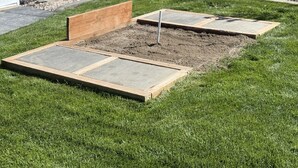Un giardino con un’aiuola rialzata e una panchina di legno.