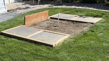 Un jardin avec un parterre surélevé et un banc en bois.