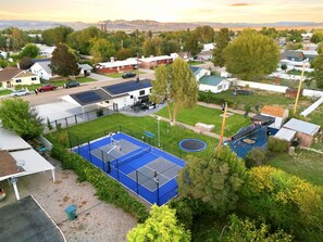 Una zona residencial con casas, una cancha de tenis azul y un trampolín.