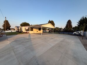 A residential area with a house, a covered patio, and a paved driveway. - Vernal Sport Court Base Camp (Vernal)