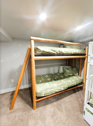 A bunk bed with a wooden frame and green patterned bedding. - Vernal Sport Court Base Camp (Vernal)
