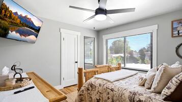 A bedroom with a bed, a desk, a chair, a ceiling fan, and a window with blinds.