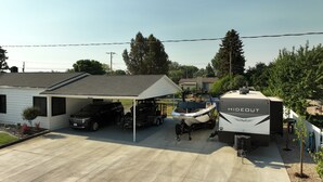 Een woongarage met een overdekte autocarport, een boottrailer en een stacaravan met de tekst 'HIDECUT'.