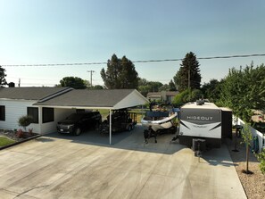 A residential garage with a covered carport, a boat trailer, and a mobile home labeled "HIDECUT." - RV full hook up  RV full hook up (Vernal)