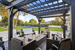 Un patio al aire libre con pérgola, zona de estar y un pozo de fuego.