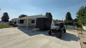 Un véhicule récréatif (VR) est garé dans une allée, avec un patio couvert et un terrain de basketball en arrière-plan.
