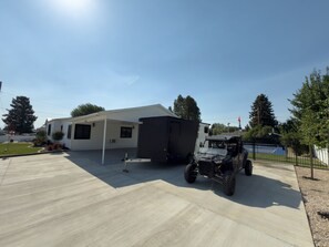 Un véhicule récréatif (VR) est garé dans une allée, avec un patio couvert et un terrain de basketball en arrière-plan.