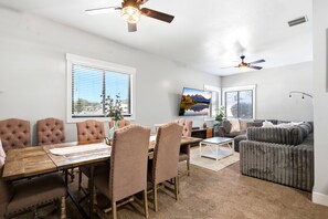 A modern living room with a dining area, featuring a wooden dining table, cushioned chairs, a grey sofa, and a flat-screen TV mounted on the wall. - RV full hook up  RV full hook up (Vernal)