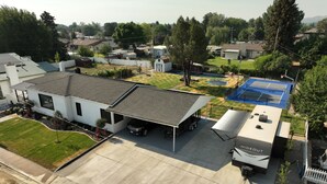 Een woonwijk met een huis voorzien van een overdekte garage, een zwembad en een stacaravan met de tekst 'HIDEOUT'.