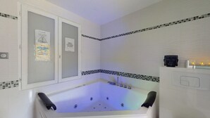 A modern bathroom with a freestanding bathtub, a window with frosted glass, and a tiled backsplash. - Kimia Suite Room (Osny)