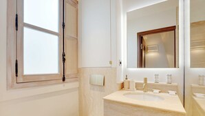 Une salle de bain moderne avec un grand miroir, un lavabo et des toilettes.