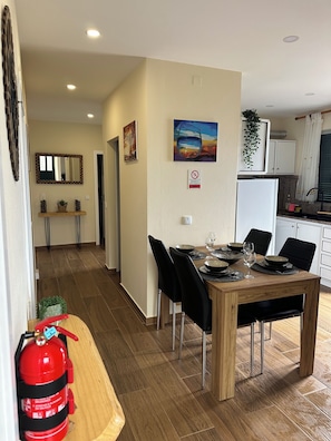 A dining area with a wooden table, black chairs, and a fire extinguisher.