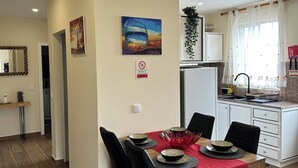 A dining area with a wooden table, black chairs, and a red tablecloth. There is a kitchen area with white cabinets and a sink. - Unforgettable Madeira Stay! Near Levada Hikes! Ocean & Mountain Views! (São Vicente, Segunda Lombada)