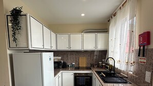 A compact kitchen with white cabinets, a built-in oven, a microwave, and a sink. - Unforgettable Madeira Stay! Near Levada Hikes! Ocean & Mountain Views! (São Vicente, Segunda Lombada)
