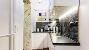 Una cocina moderna con encimeras de mármol, armarios blancos y suelo con estampado de espiga.