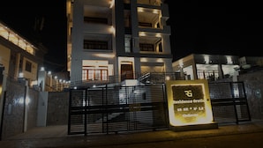 Un edificio moderno de varios pisos con entradas iluminadas y un cartel llamativo que indica "Residence Gratia".