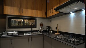 Una cocina con armarios de madera, un lavamanos de acero inoxidable, una ventana y una estufa a gas.