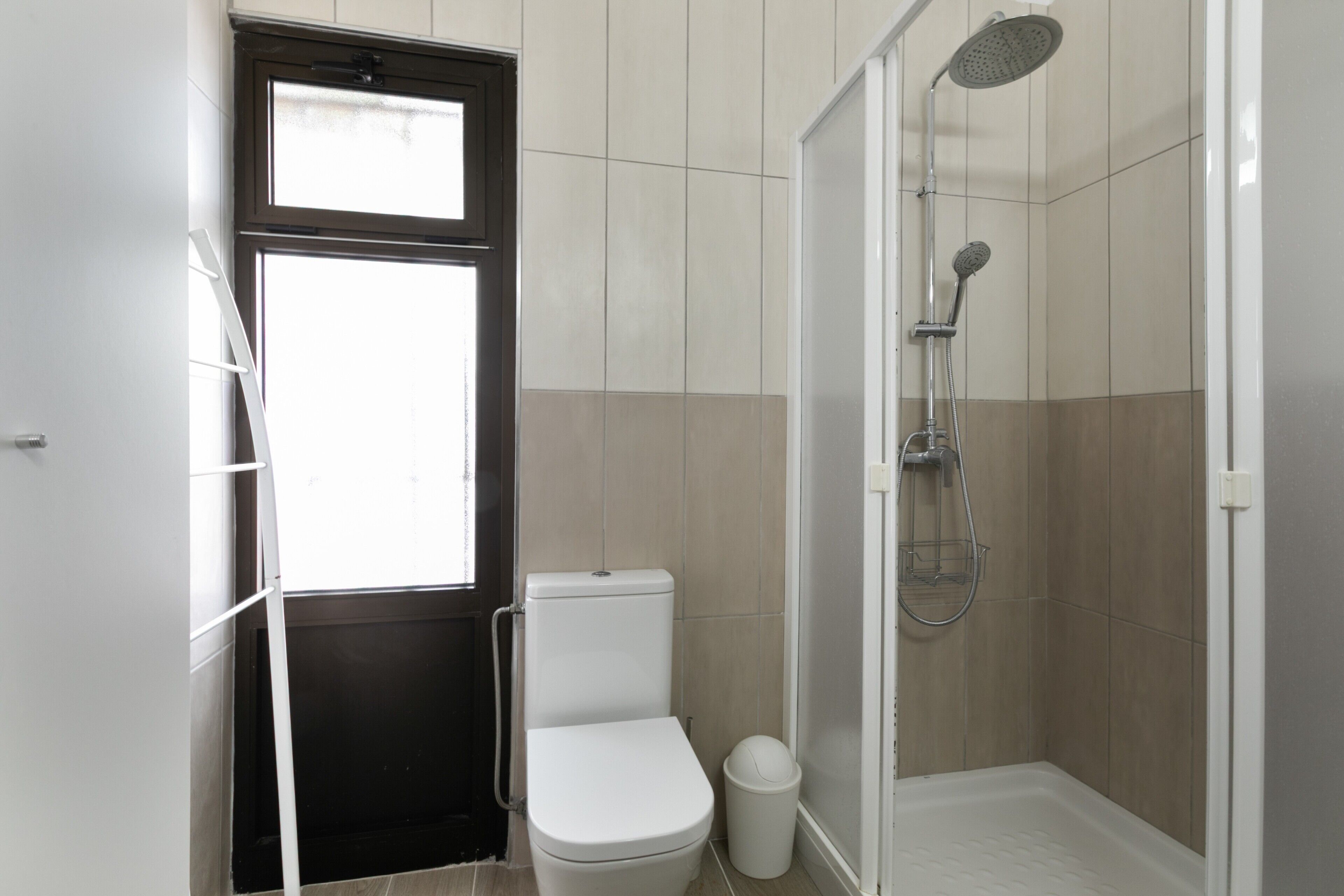 A bathroom with a toilet, a shower, and a door with a window.