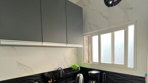 A modern kitchen with dark cabinetry, a stainless steel sink, and a window providing natural light. - Parque Rodó | Private terrace | BBQ (Montevideo)