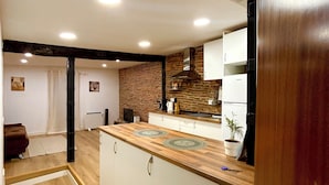 Una cocina moderna con encimera de madera, armarios blancos y pared de ladrillo.