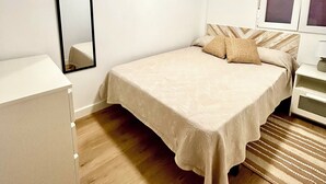 Un dormitorio con una cama, una mesita de noche, un espejo y un armario.