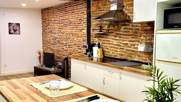 Una cocina moderna con salpicadero de ladrillo, armarios blancos y encimera de madera.