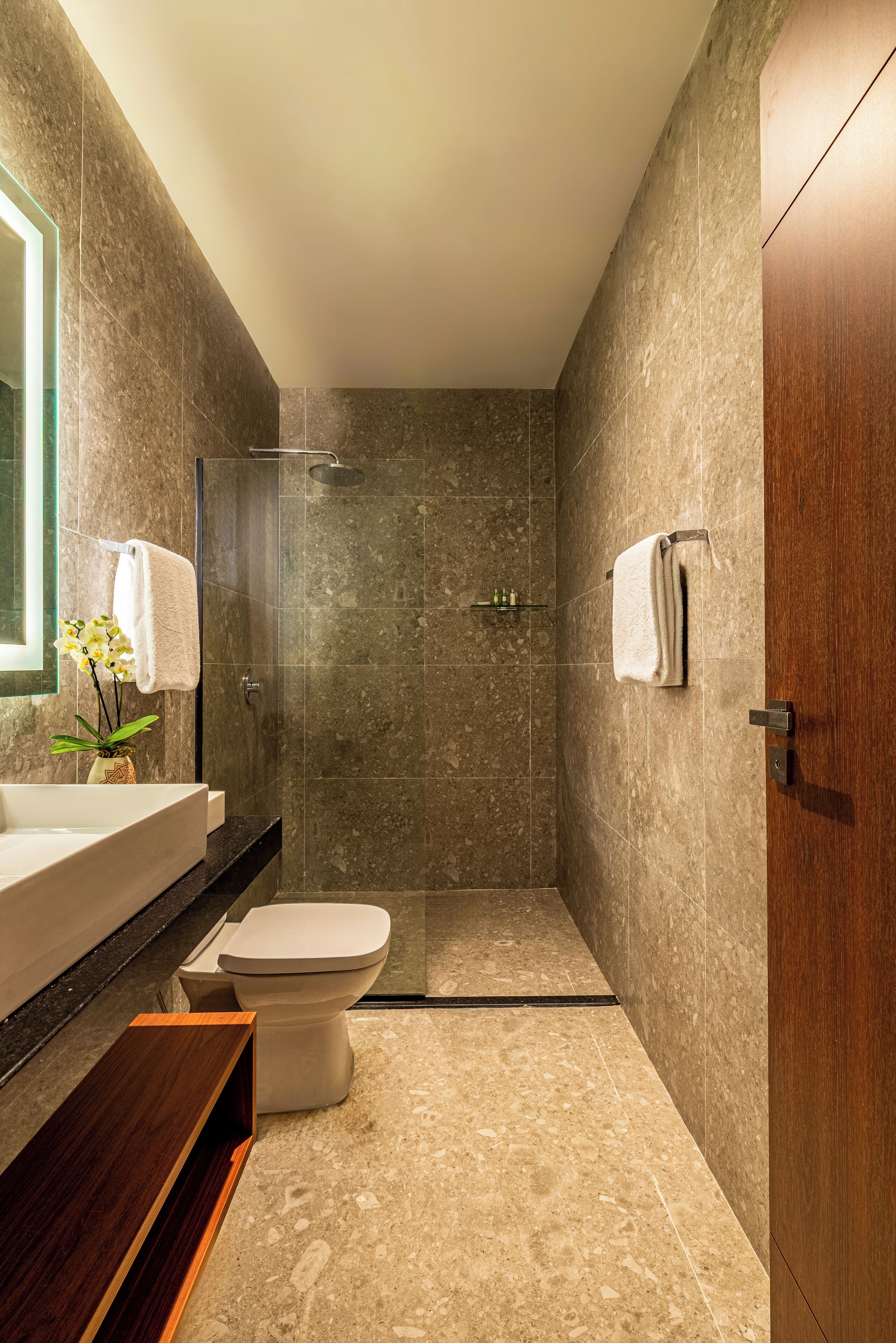 A modern bathroom with a large mirror, a sink, a toilet, and a shower area.