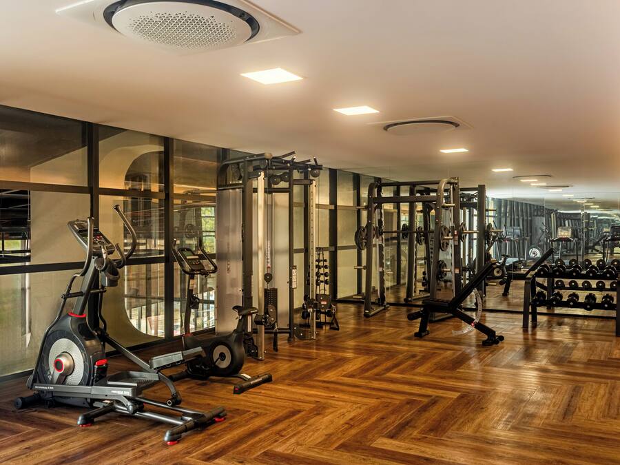 A gym with exercise equipment, wooden flooring, and large windows.