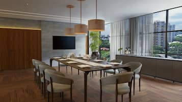 A modern dining room with a long table, multiple chairs, hanging light fixtures, a flat-screen TV, and a large window with a city view.