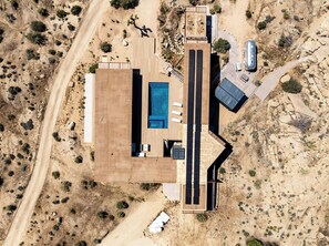 Ein Luftbild eines modernen Hauses mit Swimmingpool, Garage und gepflasterter Auffahrt.
