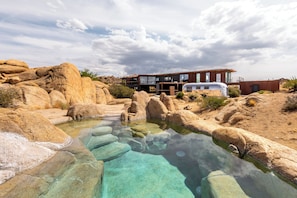 Une maison moderne avec une piscine, entourée de gros rochers.