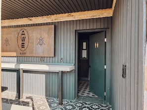 A bar with a wooden signboard, a tiled floor, and a green door. - Iconic 7,000sf Glass Villa w/ 2 Pools on 350 Acres (Pioneertown)